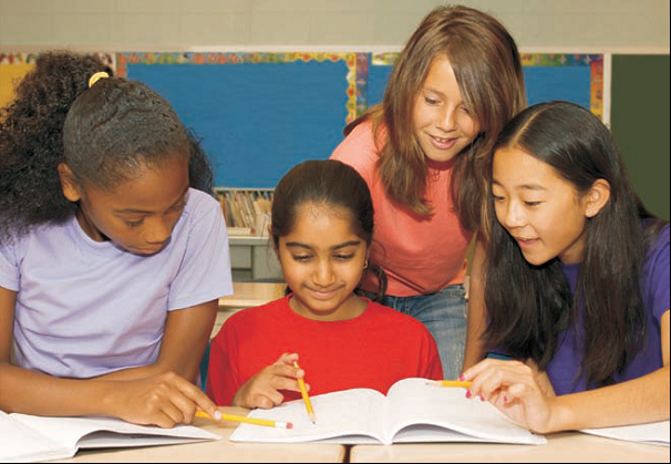 Three female students and a female teacher veiwing a textbook